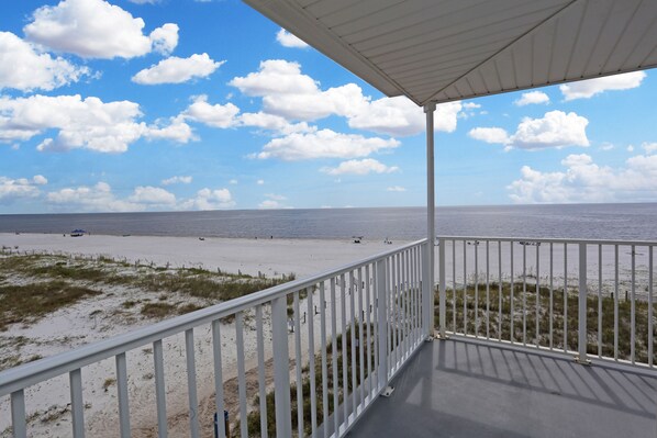 A balcony with a view of the beach and ocean.