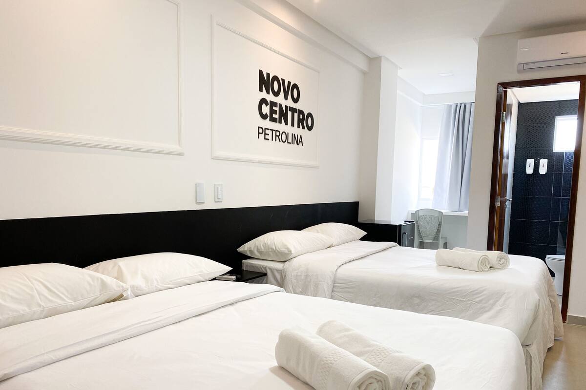 Ein Hotelzimmer mit zwei Betten, einem Schreibtisch und einer Dusche.