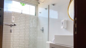 A modern bathroom with a glass-enclosed shower, a white toilet, and a sink with a mirror.