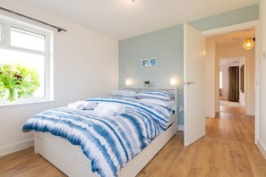 A bedroom with a bed, a window with a view, a door leading to another room, and a wall with a picture. - Faraway: Pet-friendly holiday home for 6 in Rhosneigr (Rhosneigr)