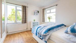 Een slaapkamer met een bed, een dressoir, een raam met gordijnen en een radiator.