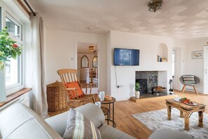 A living room with a fireplace, a television, and a dining area. - Faraway: Pet-friendly holiday home for 6 in Rhosneigr (Rhosneigr)