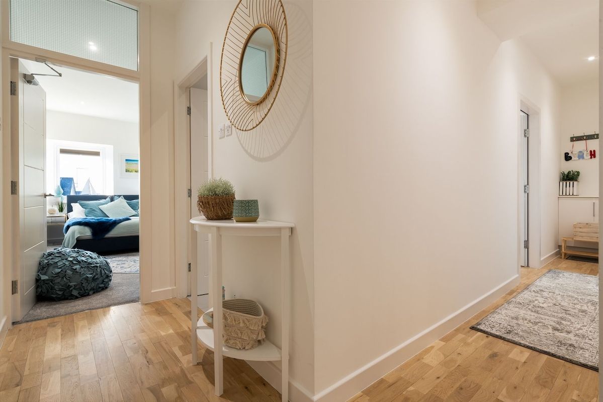 Internal hallway with coastal mirror connecting bedrooms and living spaces, renovated holiday apartment in Rhosneigr, Anglesey
