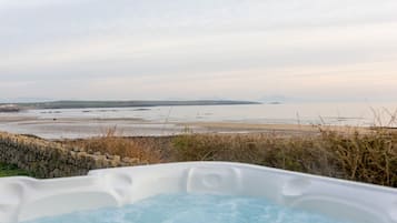 Un bain à remous avec vue sur une plage et des montagnes lointaines.