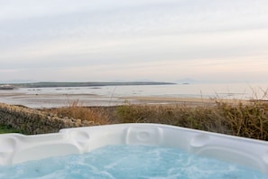 Een jacuzzi met uitzicht op een strand en verre bergen.