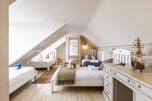 Un dormitori amb una zona de dormir en alt i una taula de treball, i un model de vaixell.