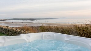 Banyera d'hidromassatge amb vista a una platja i muntanyes llunyanes.