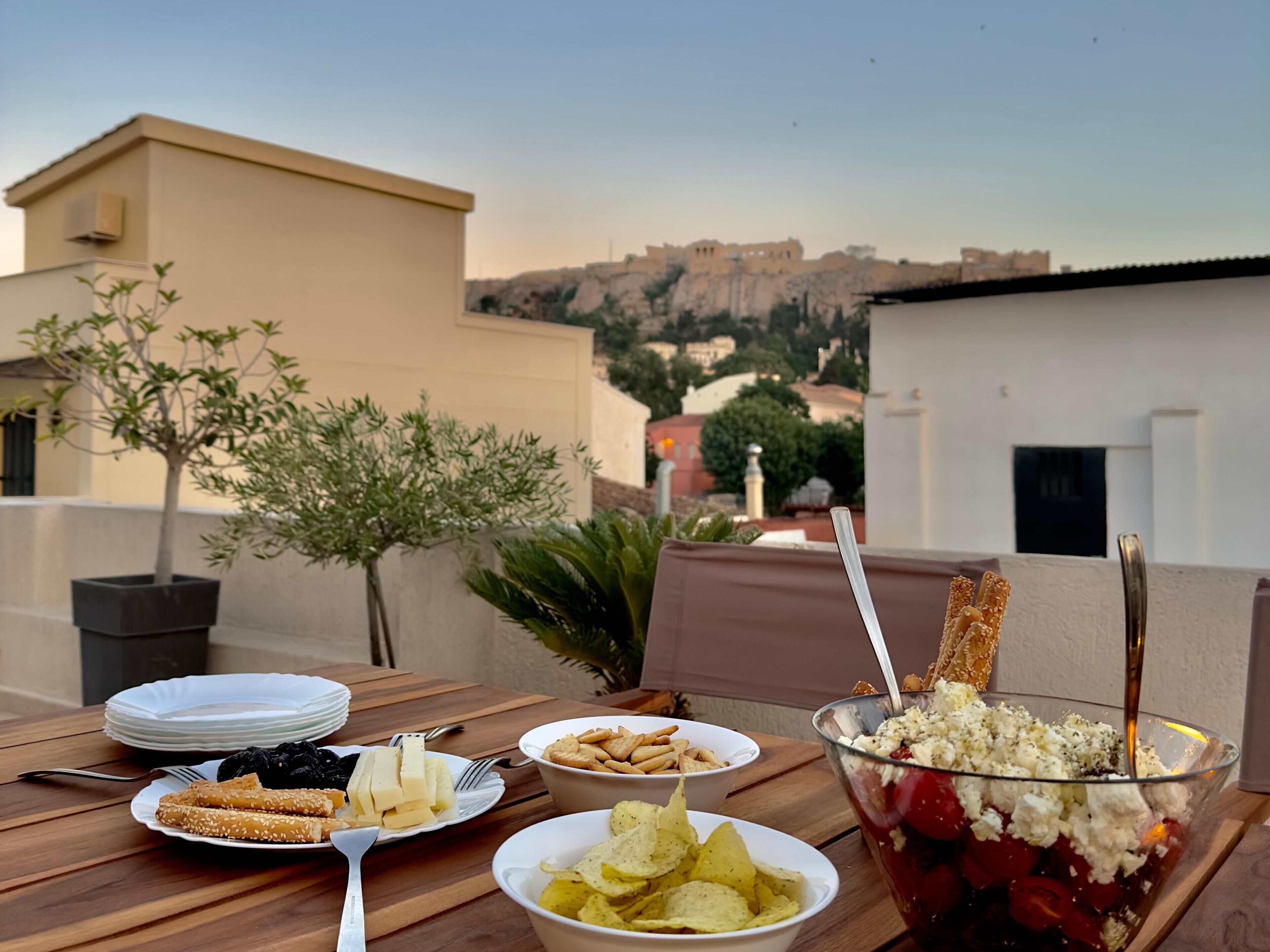 Una mesa de comedor con platos de comida, un tazón de ensalada y una vista de un edificio histórico al fondo.