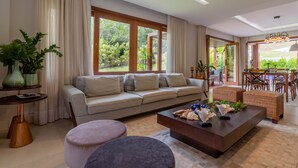Un salon moderne comprenant un canapé, des poufs, une table basse et un coin repas avec des chaises et une table.