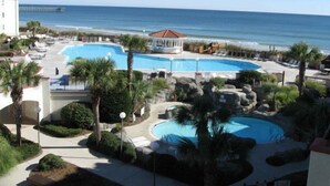 A resort with multiple swimming pools, palm trees, and a beach view.