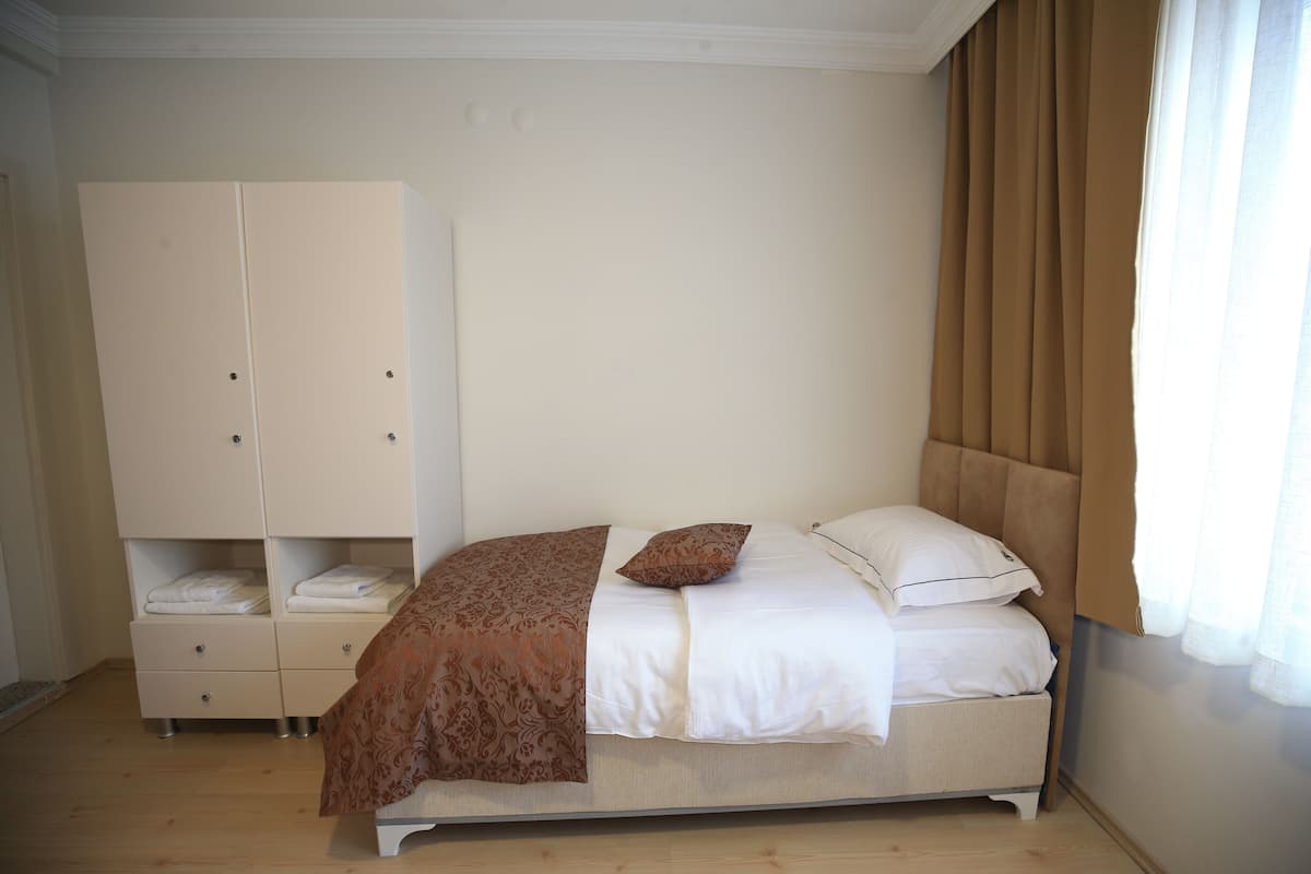 Un dormitorio con cama, armario y ventana con cortinas.