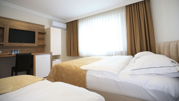 A hotel room with two beds, a desk with a television, and a minibar. - Evim Butik Hotel (Kirklareli)