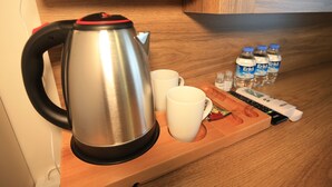 A stainless steel kettle, two white mugs, and three bottles of water on a wooden tray. - Evim Butik Hotel (Kirklareli)