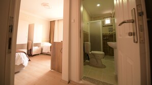 A hotel room with a bed, a chair, a bedside table, and a bathroom with a toilet, shower, and sink. - Evim Butik Hotel (Kirklareli)