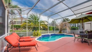 A covered outdoor area with a swimming pool, lounge chairs, and a table with chairs. - "southern Charm" 4 Bed & 2 Bath Private Pool Home 4 Bedroom Villa by RedAwning (Davenport)