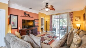 A living room with a sofa, television, and decorative items. - "southern Charm" 4 Bed & 2 Bath Private Pool Home 4 Bedroom Villa by RedAwning (Davenport)