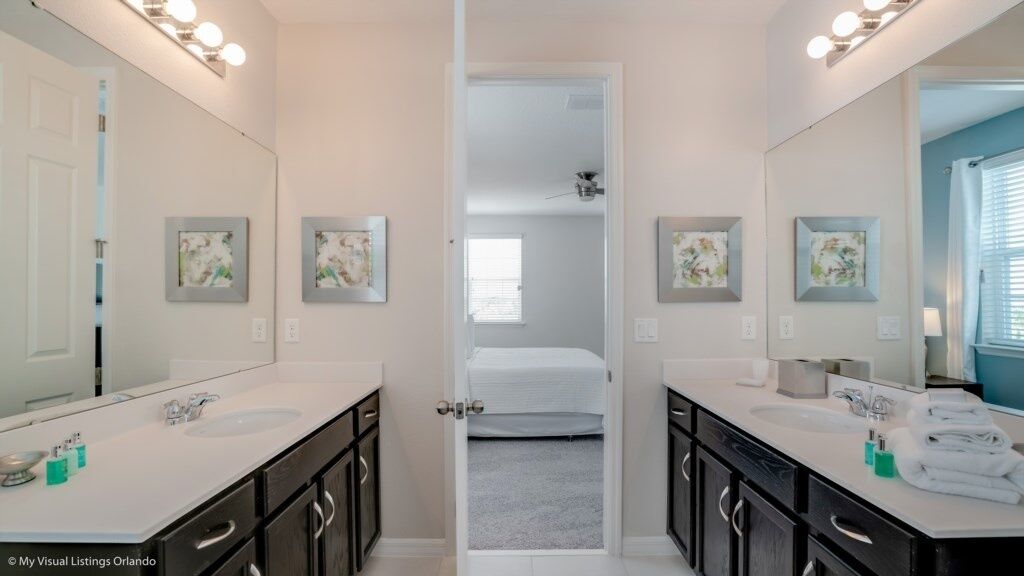 A bathroom with two sinks, dark cabinets, and framed artwork on the walls.