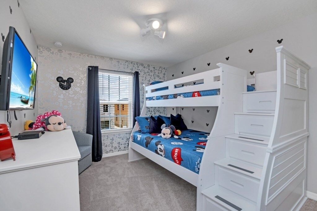 A child's bedroom with bunk beds, a desk, and a television.
