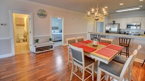 A spacious dining area with a wooden table and chairs, a chandelier, and a kitchen with modern appliances. - 4827 Magnolia Lake Drive, #302 3 Bedroom Condo by RedAwning (Myrtle Beach)