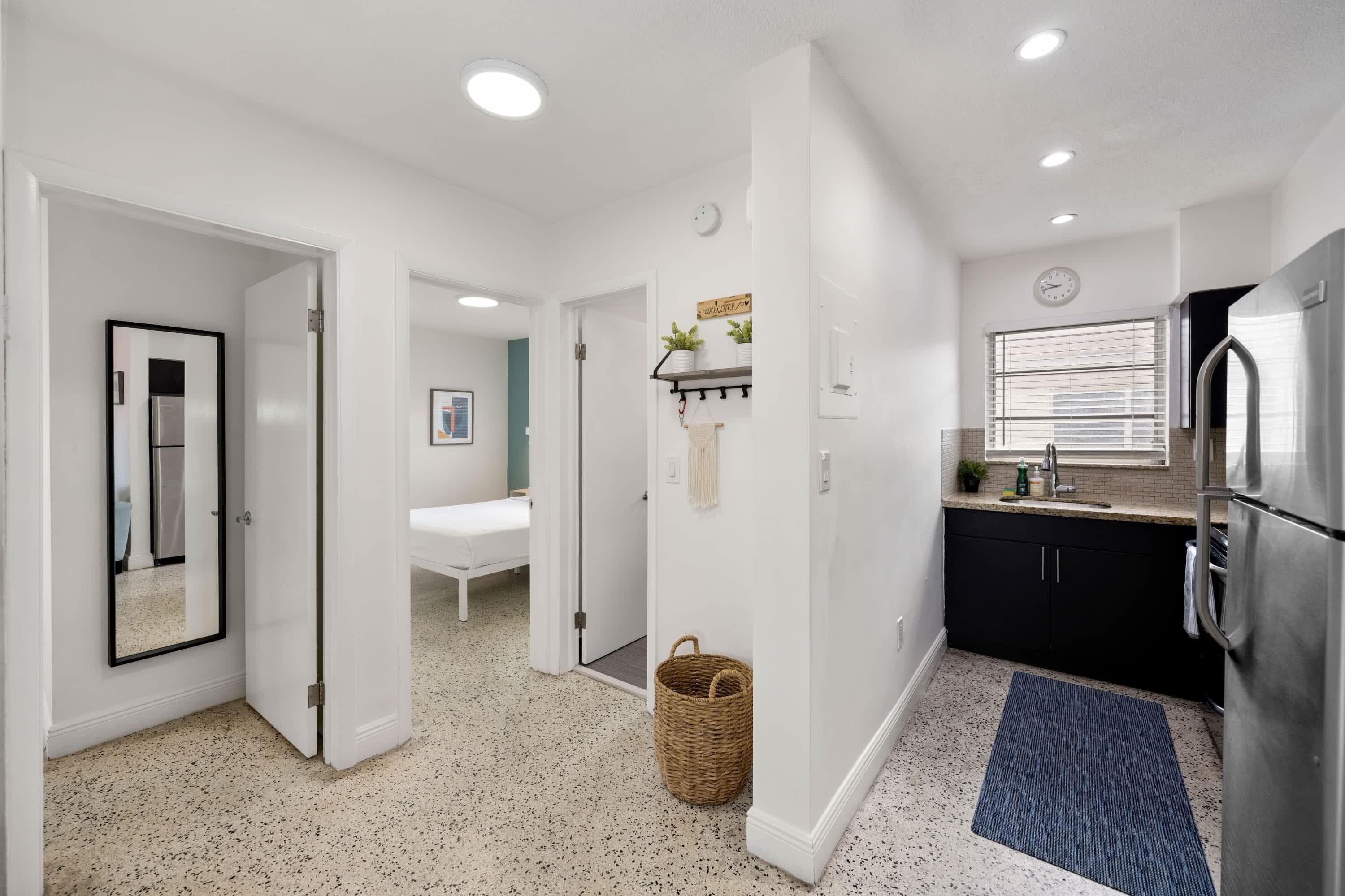 A modern kitchen with a refrigerator, sink, and window with blinds.