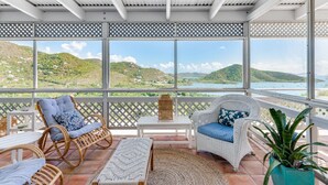 Un espace extérieur aménagé, abrité et doté de meubles en osier, d’un tapis tissé et offrant une vue sur un paysage vallonné.