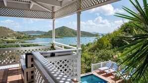 Un espace extérieur abrité comprenant une piscine, des chaises longues et une vue sur une baie où sont amarrés des bateaux.