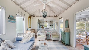 Une pièce confortable avec un lit, deux fauteuils en osier, une petite table et un buffet.
