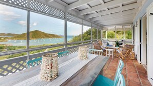 Un espace extérieur abrité, aménagé pour s’asseoir, avec vue sur la mer et les collines.