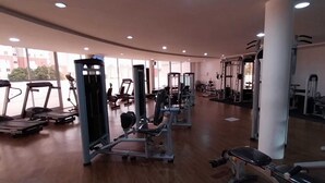 Une salle de sport spacieuse équipée de tapis de course, d’appareils de musculation et de poids libres.