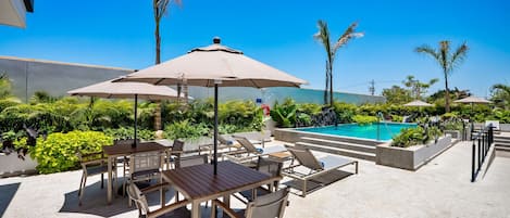 A poolside area with lounge chairs, a table, and umbrellas.