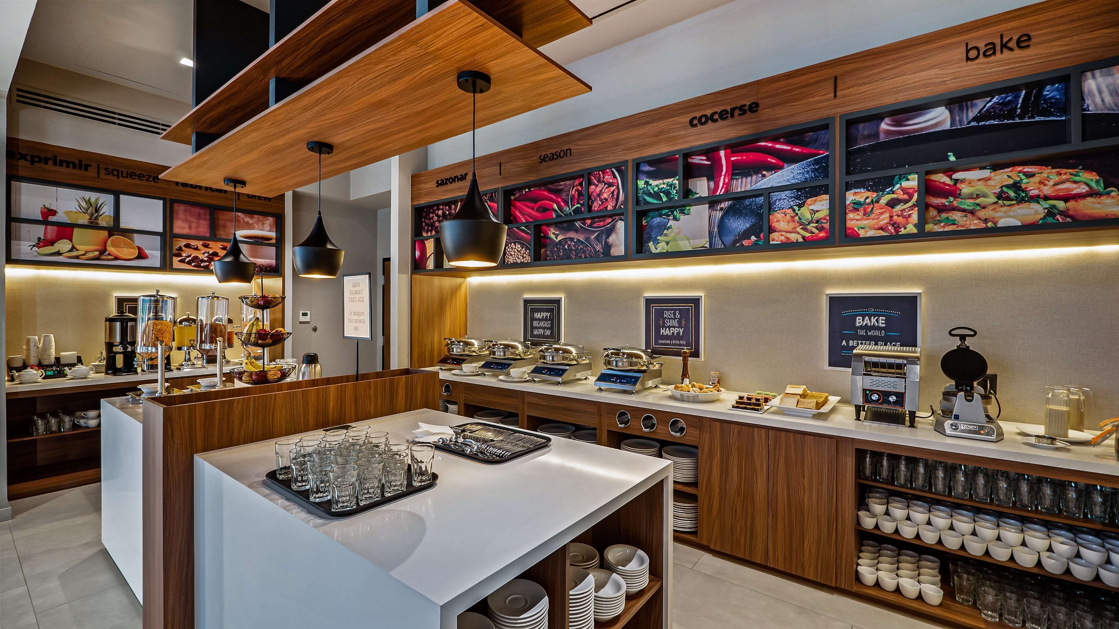 A modern breakfast bar with a wooden ceiling, a coffee station, and a wall displaying seasonal food images.