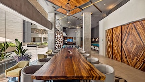Un vestíbulo amplio con un mostrador de recepción de madera, asientos cómodos y un moderno candelabro.