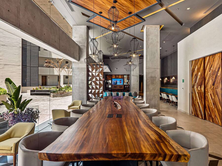 Un vestíbulo amplio con un mostrador de recepción de madera, asientos cómodos y un moderno candelabro.