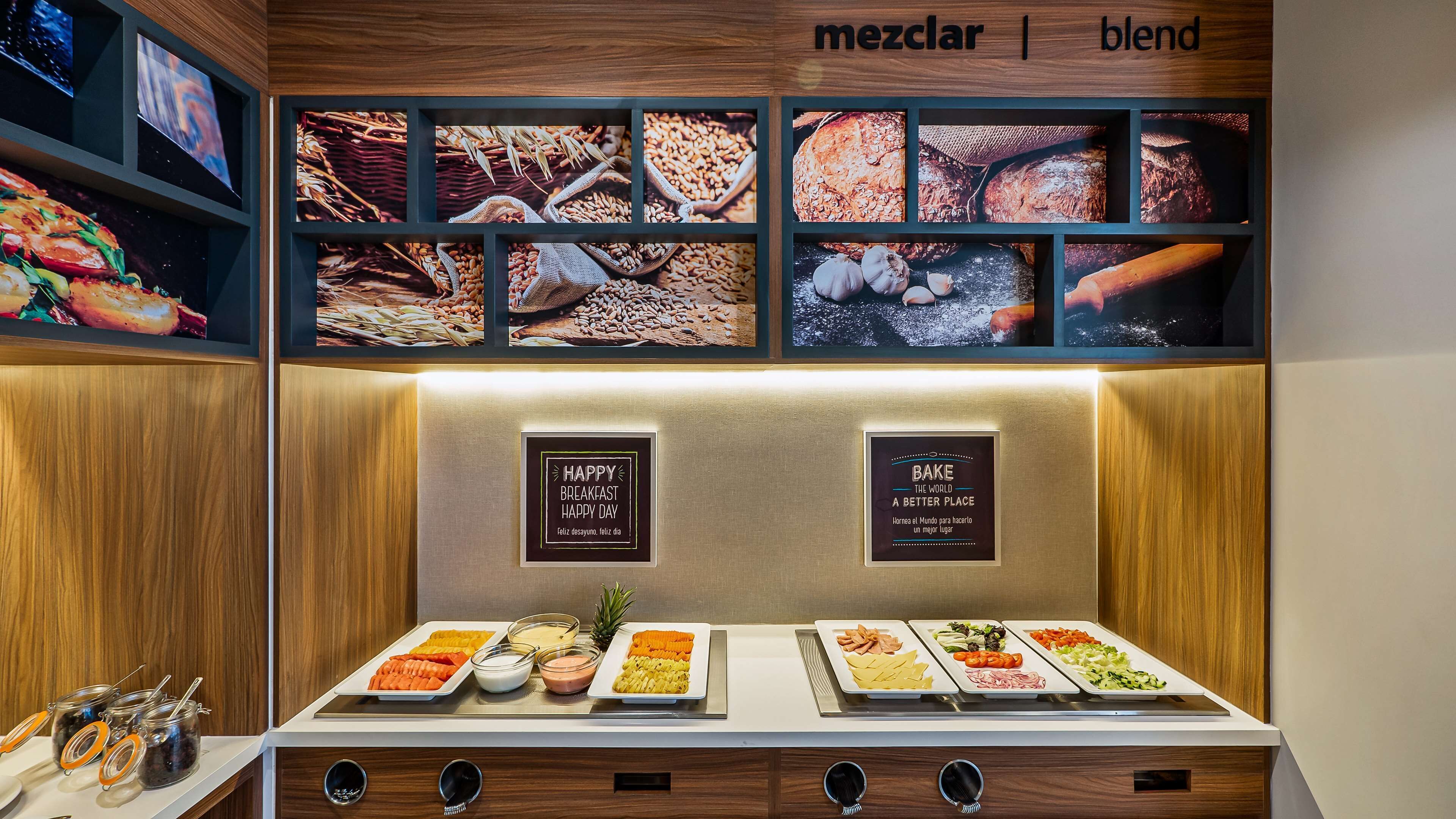 Un bufé de desayuno con diversas opciones de alimentos y una pared que exhibe imágenes de cereales y pan.