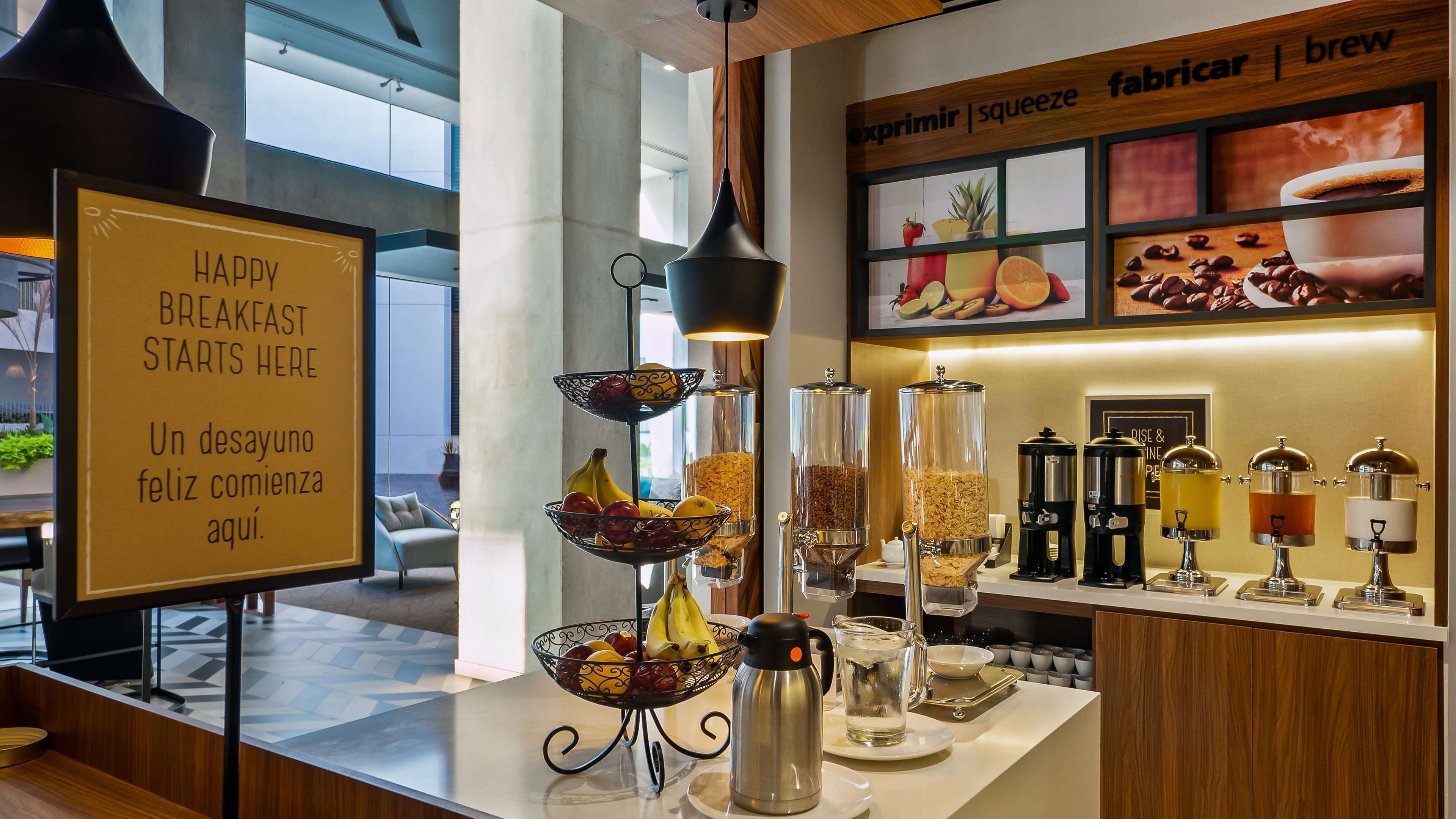A breakfast area with a sign reading "HAPPY BREAKFAST STARTS HERE" and a variety of food and drink dispensers.