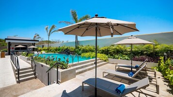Una piscina al aire libre, sillones reclinables de piscina