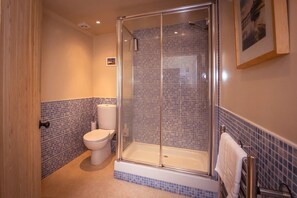 A bathroom with a glass-enclosed shower, a toilet, and a bathtub.