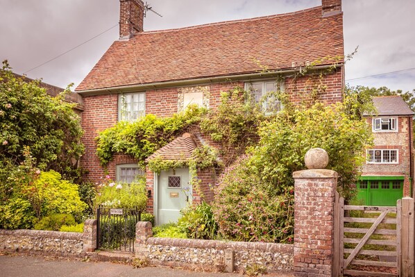 A traditional brick house with a tiled roof, ivy-covered walls, and a front gate.