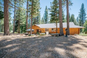 A wooden cabin surrounded by tall pine trees. - Granite Getaway: Spacious and Beautiful, Hot Tub, Dog Friendly, Backs Forestland by Tahoe Time VR (Carnelian Bay)