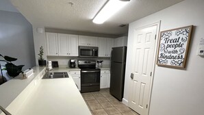 Una cocina moderna con armarios blancos, electrodomésticos de acero inoxidable y una isla de cocina.