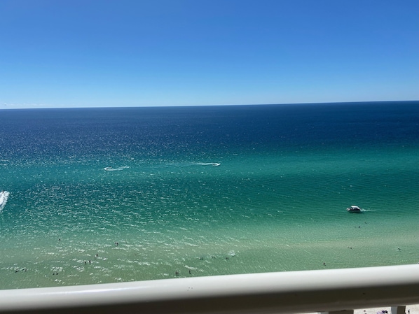 A view of a beach with clear turquoise waters and a few people in the distance. - Beachfront Condo with Beautiful Gulf Views. (Panama City Beach)