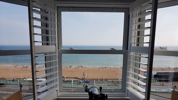 Een kamer met een groot raam met uitzicht op een strand.