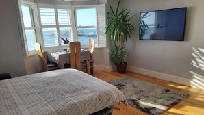 Een slaapkamer met een bed, een bureau, een stoel, een potplant en een televisie.