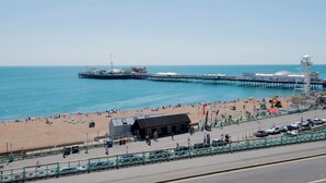 Een strand met een pier die zich uitstrekt in zee, een redershut en een klein gebouw met de tekst 'Vision Electric Station'.