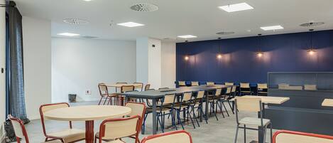 A conference room with round tables and chairs, a dark blue accent wall, and recessed ceiling lights.