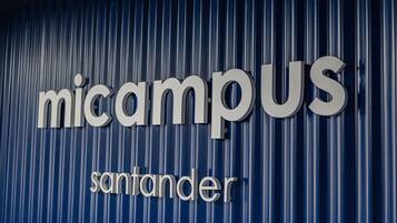 Un letrero con las palabras 'micampus' y 'santander' sobre un fondo de lámina corrugada.