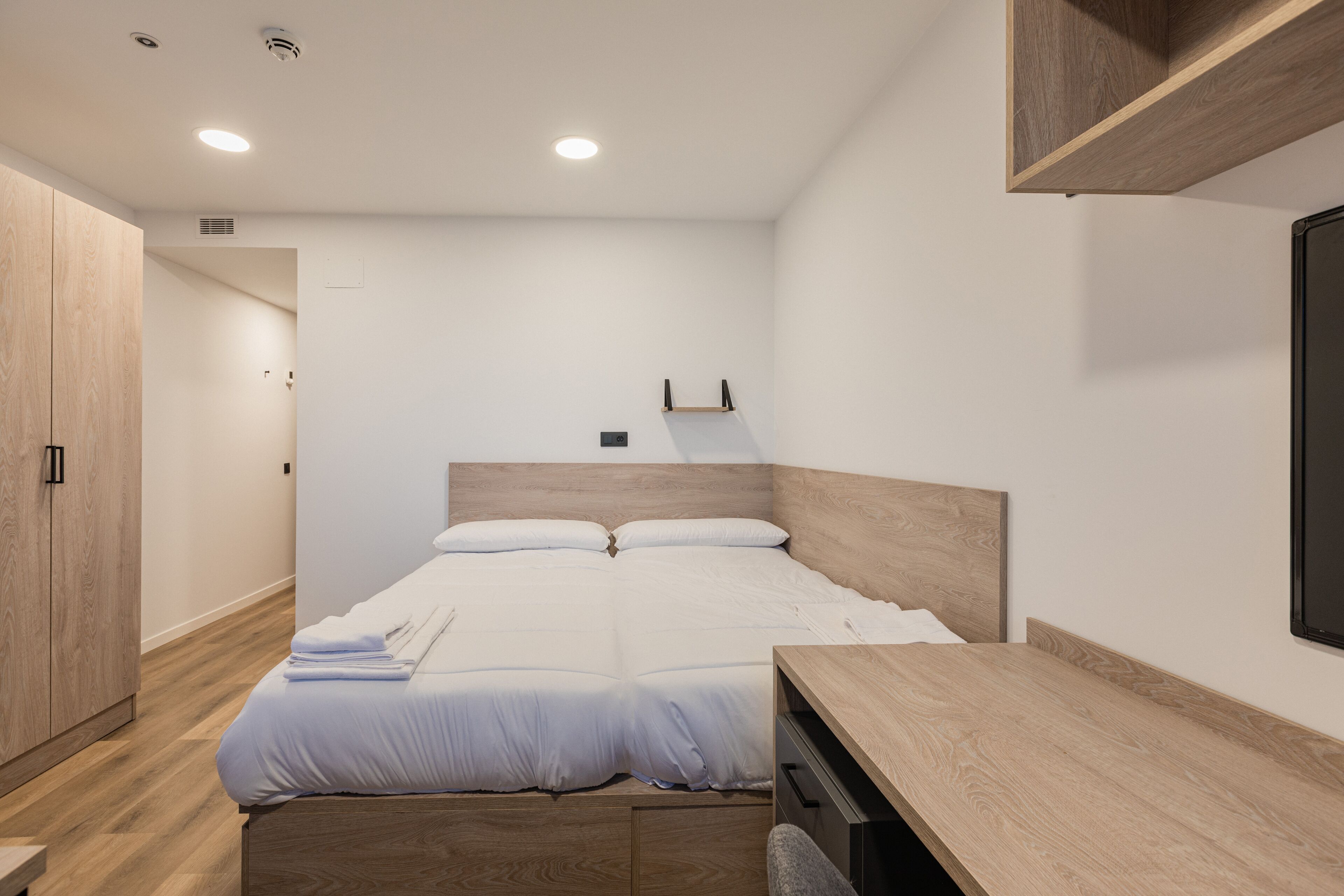 Ein modernes Schlafzimmer mit einem hölzernen Bett, einem Schreibtisch und einem Kleiderschrank.