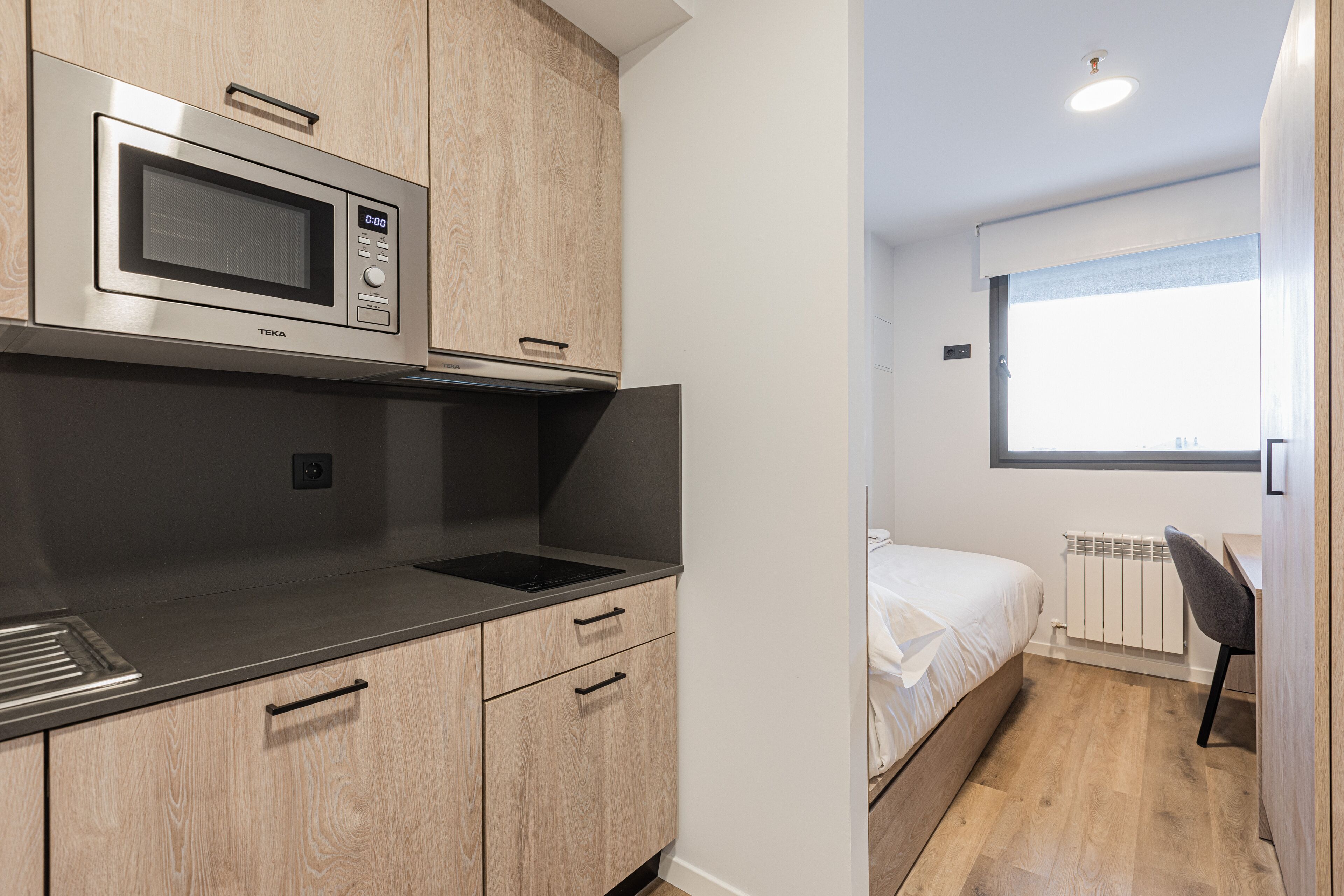 A compact kitchen with a microwave, a sink, and wooden cabinets.