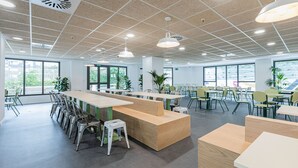 Uma sala de conferências moderna com mesas compridas, cadeiras e uma escrivaninha de madeira central.