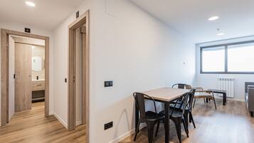 Una cocina moderna con encimera de madera, una mesa de comedor con sillas y un amplio ventanal que proporciona luz natural.
